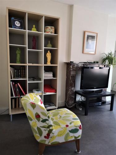 a living room with a chair and a tv at Aux Herbes Folles in Herve