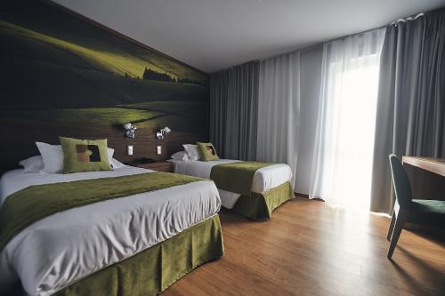 a hotel room with two beds and a window at Hotel Cruzeiro in Angra do Heroísmo
