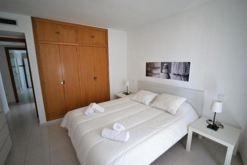 ein Schlafzimmer mit einem weißen Bett mit Handtüchern darauf in der Unterkunft Stay In Mediterranean View in El Campello
