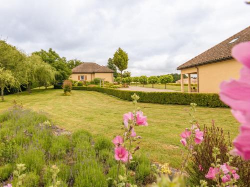a yard with pink flowers and a house at Modern holiday home with swimming pool in Saint-Nexans