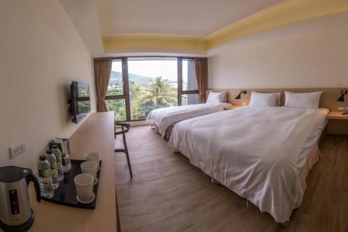 a hotel room with two beds and a large window at KET Hotel in Yuli