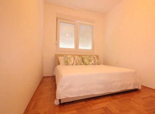 a bedroom with a white bed with a window at Apartment Ema in Trebinje