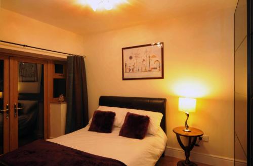 1 dormitorio con 1 cama con 2 almohadas y lámpara en Orchid House en Southport