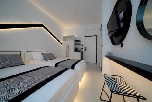 a bedroom with two beds and a tv on the wall at Divelia Hotel in Perissa