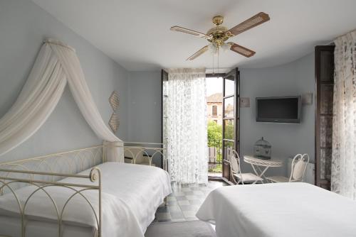 a bedroom with two beds and a ceiling fan at Pension Venecia Gomerez in Granada