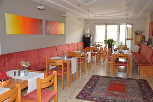 a restaurant with tables and chairs and a red couch at Gästehaus Schmidt in Podersdorf am See