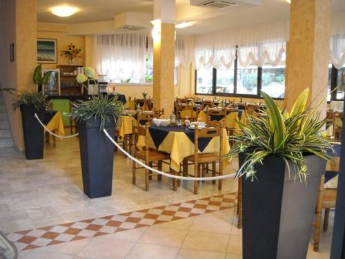 un restaurante con mesas y sillas con plantas. en Albergo Santo Stefano, en Bellaria-Igea Marina