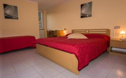 a bedroom with a large bed with a red blanket at Hotel Ristorante Miravalle in Teglio
