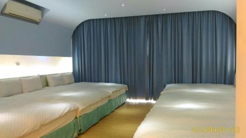 2 camas en una habitación de hotel con cortinas azules en SKY square Homestay, en Magong