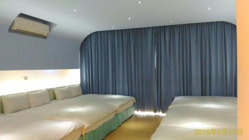 2 camas en una habitación de hotel con cortinas azules en SKY square Homestay, en Magong
