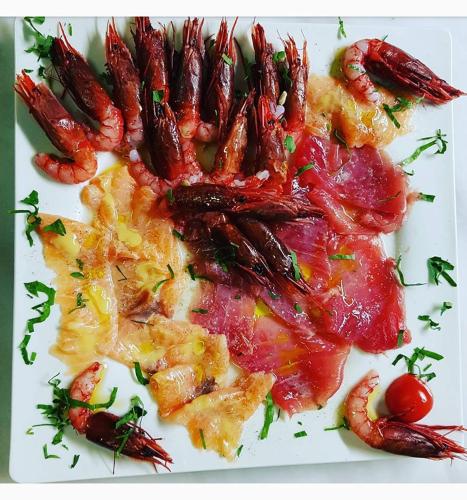 a white plate of food with shrimp and tomatoes at L'Angolo Di Beppe in Torre Lapillo