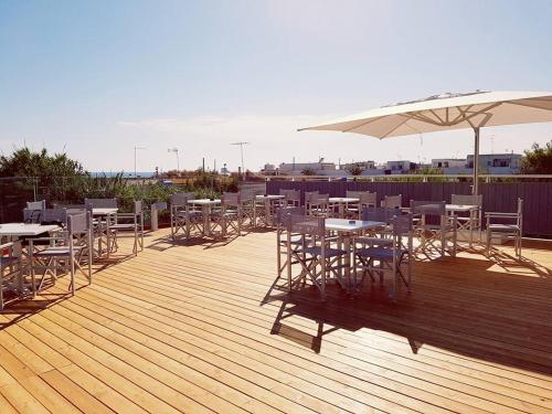 a deck with tables and chairs and an umbrella at L'Angolo Di Beppe in Torre Lapillo