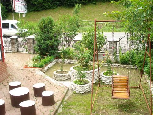 a garden with a bench and some trees and plants at Садиба Тушер in Rakhiv