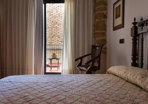 a bedroom with a bed and a chair and a window at Cal Tomas, Ecoturisme Terra Alta in Bot