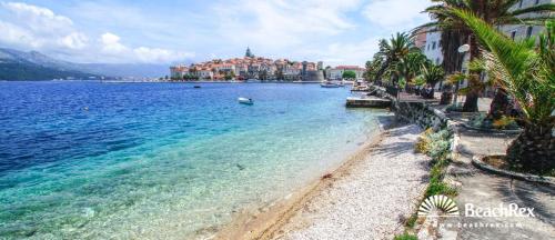 a beach with palm trees and a town in the background at Apartments Jasmina in Korčula