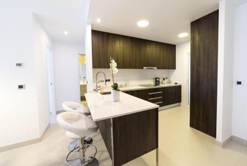 cocina con encimera blanca y armarios de madera en Benidorm Luxury Residential, en Benidorm