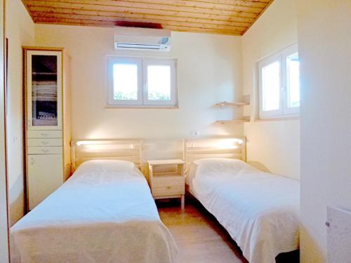 two beds in a room with two windows at Apartments Mladen in Njivice