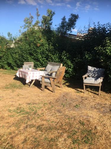 two benches and a table and a chair in a yard at Farbror Alfreds Sjöutsikt in Köpingsvik
