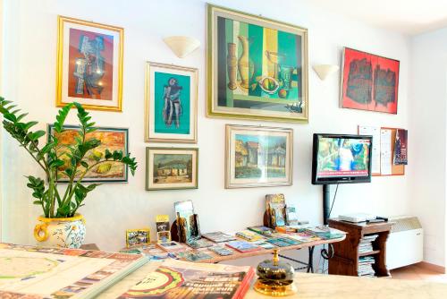 サンタ・マリア・デル・ジューディチェにあるHotel Ristorante da Carlosのテーブル、テレビ、壁画が備わる客室です。