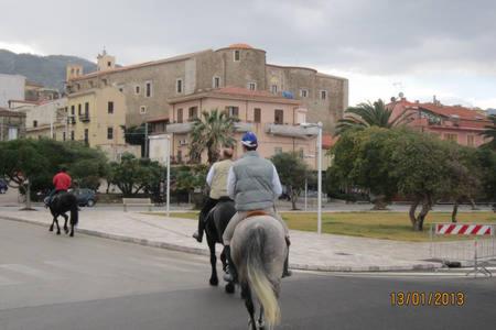 a group of people riding horses down the street at Pietra di mare in SantʼAgata di Militello