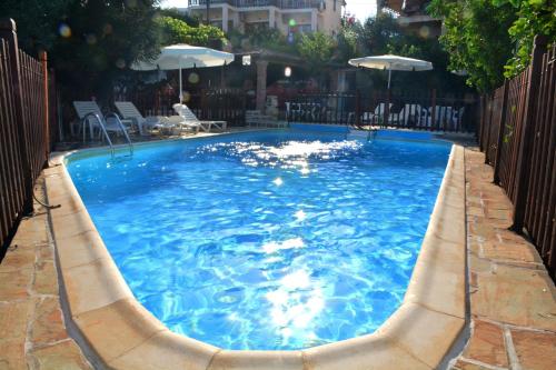 a large blue swimming pool with chairs and umbrellas at Voula Apartments in Agia Marina Aegina