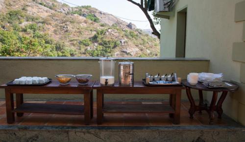 two tables on a porch with food and drinks at The Colonial Manek Manor By SAH in Mount Ābu