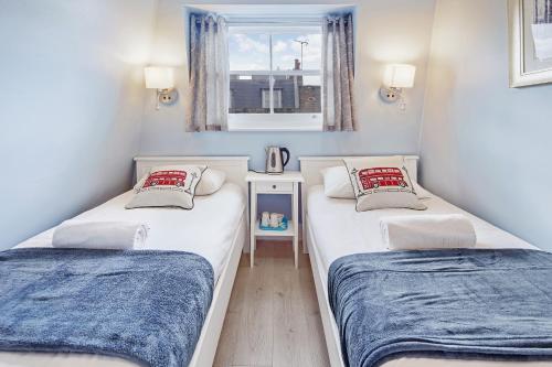 2 łóżka w małym pokoju z oknem w obiekcie Astor Kensington Hostel w Londynie