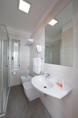 Un baño blanco con lavabo e inodoro. en Hotel Simi Lan, en Lignano Sabbiadoro