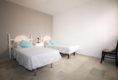 Castillo de SabinillasにあるPuerto de la duquesa beach apartmentの白い壁の客室で、ベッド2台、青い枕が備わります。