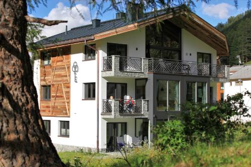 a large white building with people on a balcony at Engadin Lodge PREMIUM & PRIVATE in Samnaun