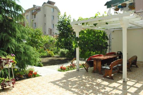 eine Terrasse mit einem Holztisch und einer Pergola in der Unterkunft Veda Guest House in Pomorie