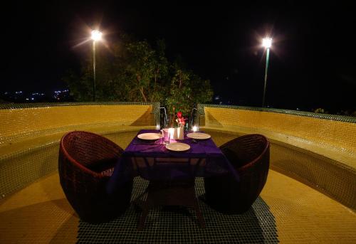 a table and chairs sitting on a balcony at night at The Colonial Manek Manor By SAH in Mount Ābu