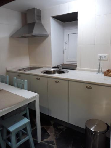 a white kitchen with a sink and a table at Sossego da Carminho in Monsaraz