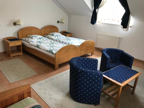 a bedroom with a bed and two chairs at Silvanus Panzió in Lenti