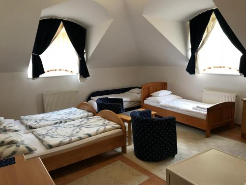 a room with two beds and two windows at Silvanus Panzió in Lenti