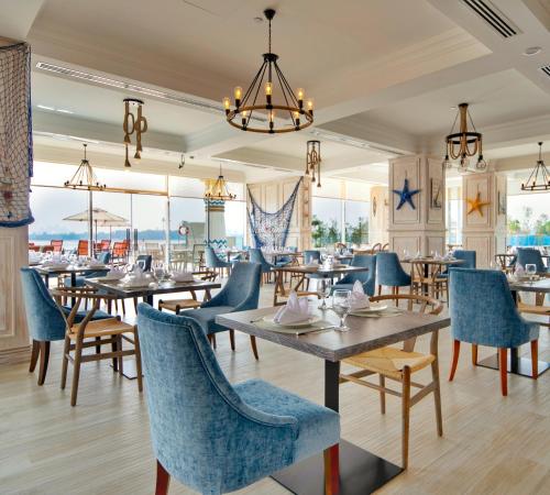 a dining room with tables and chairs and windows at Royal Central Hotel and Resort The Palm in Dubai