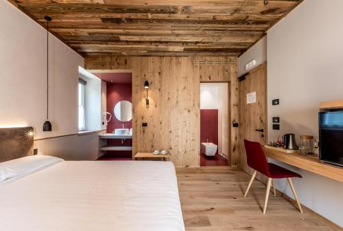 1 dormitorio con 1 cama blanca y 1 silla roja en Good Life Hotel Garden en Ledro