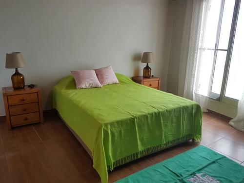 a bedroom with a green bed with two night stands at Amazing view to the sea & port bay in Mosteiros in Mosteiros