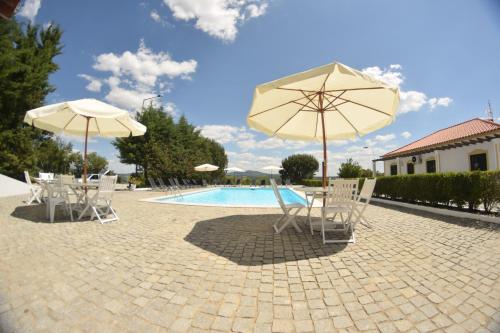 a group of chairs and umbrellas next to a pool at Quinta da Nave do Lobo in Marvão