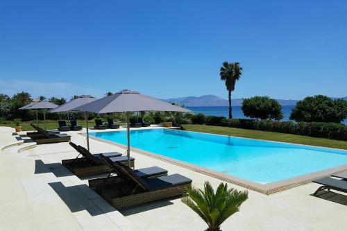 a swimming pool with chairs and umbrellas at Therme Sea Luxury Lodge in Thermisia