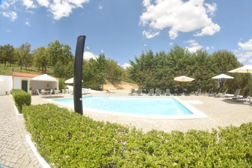 a beach area with a pool, chairs, and umbrellas at Quinta da Nave do Lobo in Marvão