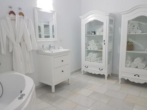 a white bathroom with a sink and a mirror at Villa Artemis in Agios Georgios