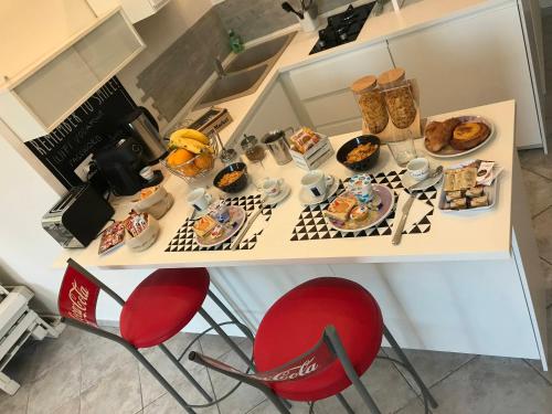 a table with plates of food and red chairs at Il BorGhetto Guest House in Civitavecchia