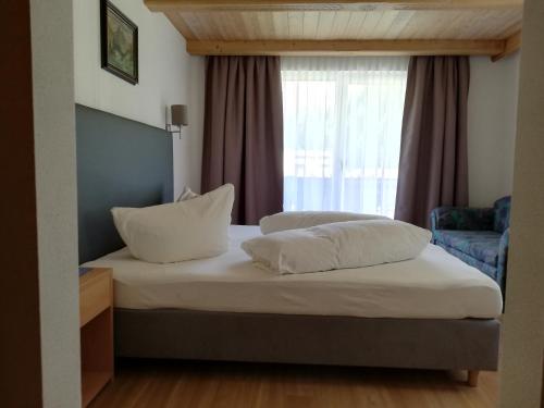 een bed met 2 kussens en een raam in een kamer bij Gschwandthof in Sankt Leonhard im Pitztal