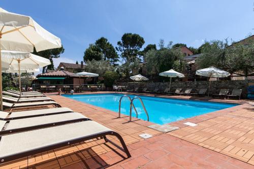 a swimming pool with lounge chairs and umbrellas at Locanda Antiche Macine in Santarcangelo di Romagna