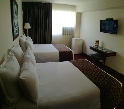 a hotel room with two beds and a television at Hotel Carrera in Lima