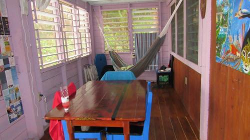 a table and chairs in a room with a hammock at Anda Di Hows Hostel in Placencia Village