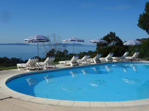 una gran piscina con sillas y sombrillas en Azur Hotel en Le Lavandou