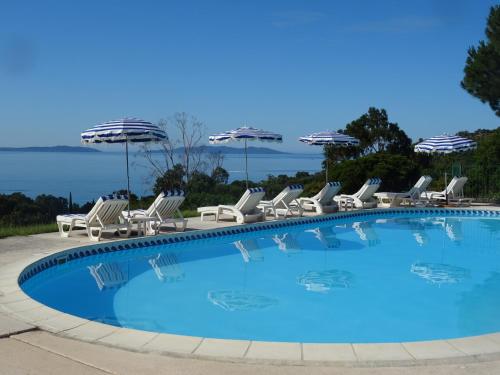 una gran piscina con sillas y sombrillas en Azur Hotel, en Le Lavandou