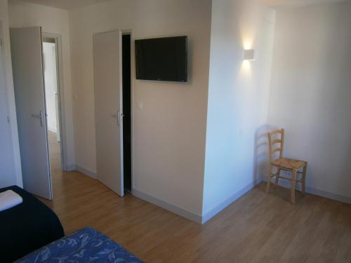 une pièce avec une télévision au mur et une chaise dans l'établissement Les Dimathal, à Mens